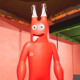 A simple red humanoid with party hats covering the two horns on its head sticking its tongue out