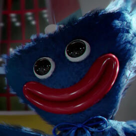 A blue fuzzy/plush creature with a wide red-lipped smile wearing a blue bowtie looking to the side blankly