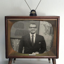 An old-fashioned television set showing the black-and-white image of a man in a black suit with the text "Cash or Ash" behind him